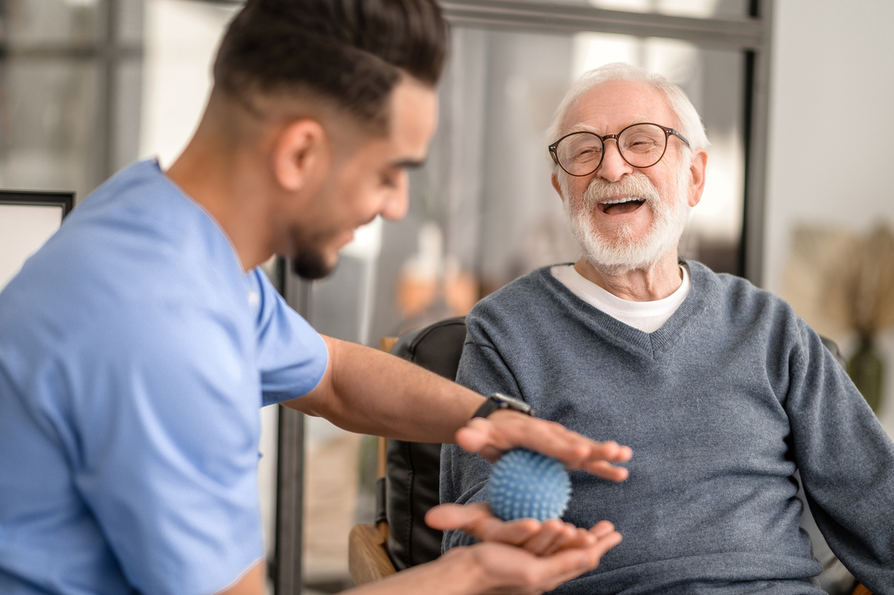 Caregiver engaging with client through therapeutic hand exercises at home